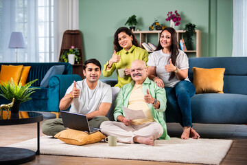 Happy indian family using laptop while sitting on sofa at home.