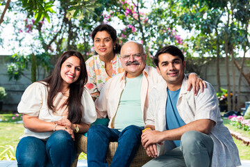 Fototapeta premium Outdoor portrait of cheerful Indian family sitting on stairs.