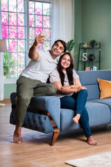 Obraz premium Happy and beautiful Indian Asian young couple using cellphone.