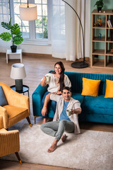 Obraz premium Cheerful young beautiful Indian couple having coffee together on sofa at home..