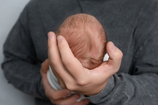 baby's head on father's hand