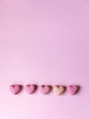 Five heart shaped pink macarons on bright pink backdrop