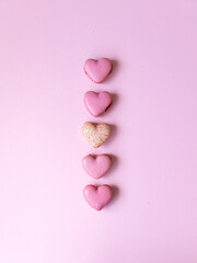 five pink heart shaped macaron cookies on pink background