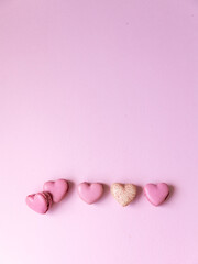 five heart shaped pink macaron cookies on pink background