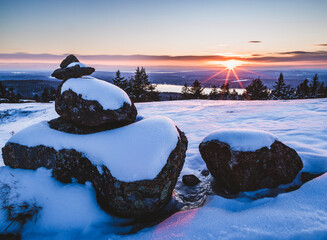 Winter sunset with pile of snow covered rocks and beautiful view.