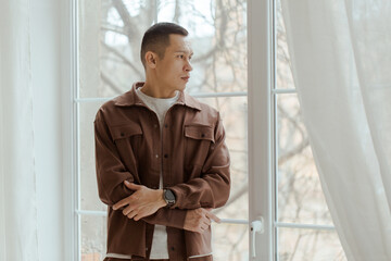Portrait of sad pensive Asian man near window