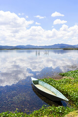 green boat on the shore of lagoon reflecting sky and mountains. beautiful landscape in mexico