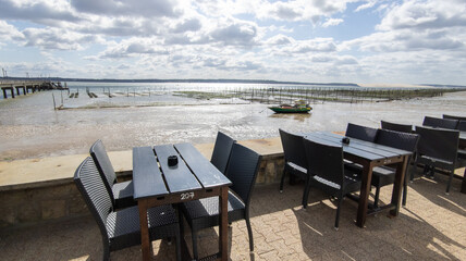 bar restaurant tables on the tip of Cap Ferret at low tide with oyster farm in Lege in Gironde...