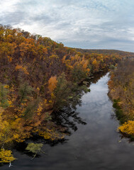 Autumn aerial panorama of colorful forest on river. Flying above autumnal vibrant Ukraine scenery
