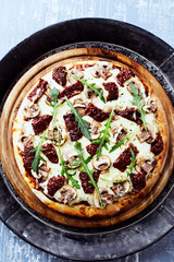 Pizza with mozzarella cheese and marinated tomatoes. Bright wooden background. Top view.	