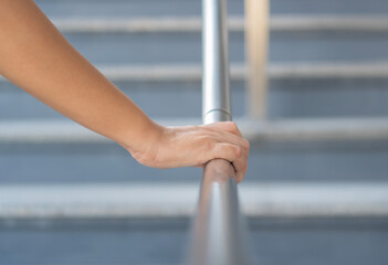 Close up shoot on a hand catching a stair rail. Woman aware about safety while walking on the stair way.