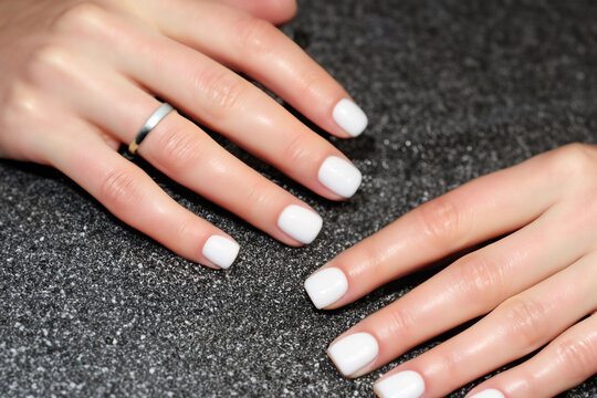 women's manicure. stylish white manicure on female hands, a silver ring is on the finger, beauty concept