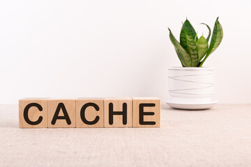 Cache word concept written in wooden cubes on a light table and a flower on a light background