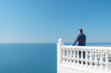 Man standing on balcony and look on the sea horizon at day.