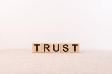 Trust word concept written on wooden cubes on a light table and a light background