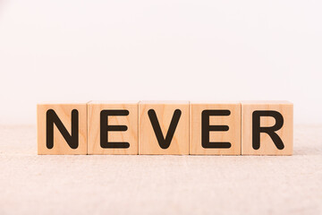 .Never word concept written on wooden cubes on a light table and light background