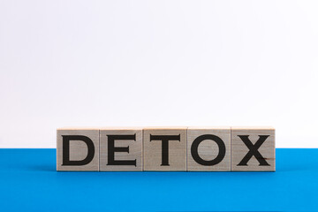 Concept word DETOX on wooden cubes on a blue background