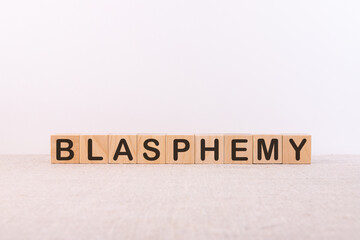 blasphemy word concept written on wooden cubes on a light table and a light background