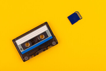 Retro audio cassette from the 80s and SD card on a yellow background. The concept of the past and...