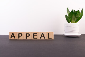 Appeal word on wooden cubes on a dark table with a flower and a light background