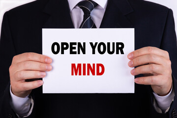 Obraz premium Businessman holding a card with text open your mind