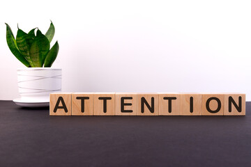 ATTENTION word concept written on wooden cubes on a dark table with a flower and a light background