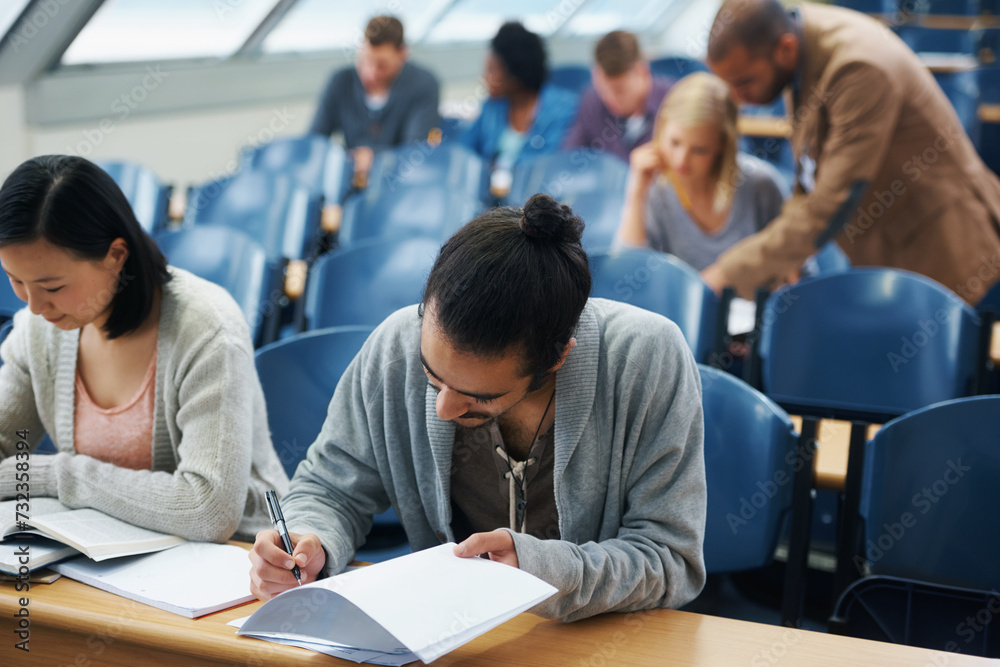 Wall mural Students, university and writing exam in classroom, information and notes for studying. People, books and knowledge in education for learning, problem solving and ideas for solution in assessment