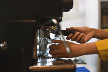 Female barista preparing espresso using coffee machine in a trendy cafe
