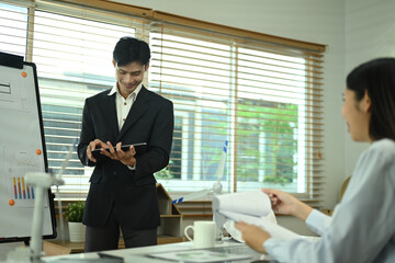 Millennial male manager using digital tablet and explaining finance sales data to his colleague