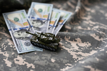 Toy tank on US hundred dollar bills banknotes close up. The concept of war costs, military spending and economic crisis