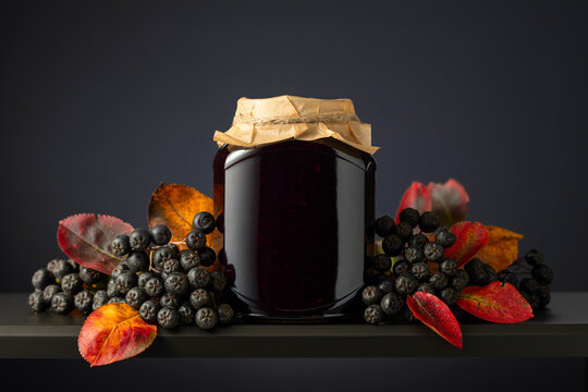 Chokeberry jam and fresh berries with leaves.