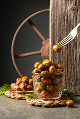 Spicy olives in a glass bowl on a stone table.