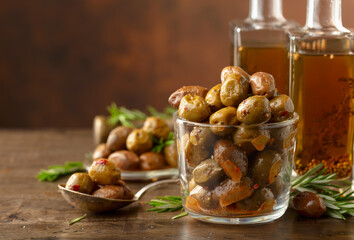 Spicy olives and bottles of olive oil on a wooden table.