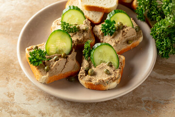 Open sandwiches with pate, cucumber, capers, and parsley.