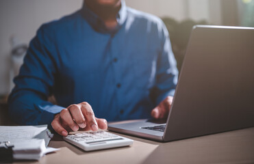 business, finance, investment, financial, document, report, budget, account, accounting, analysis. close-up view of businessman using calculator and a laptop computer to analyze business and finance.
