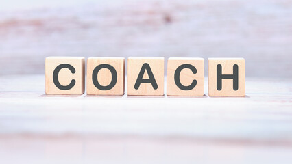 COACH word made of wooden cubes on a light background