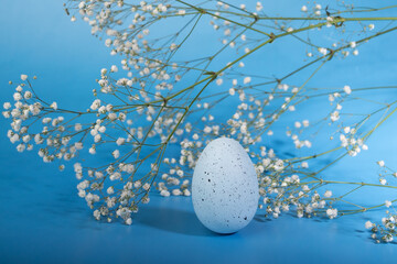 Decorated Easter egg with flowers, blue backdrop, spring decor