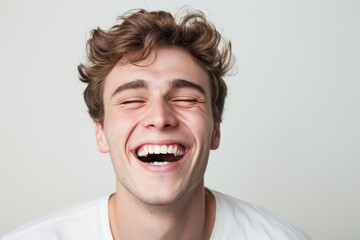 Joyful young man laughing against plain background. Human emotion and expression.