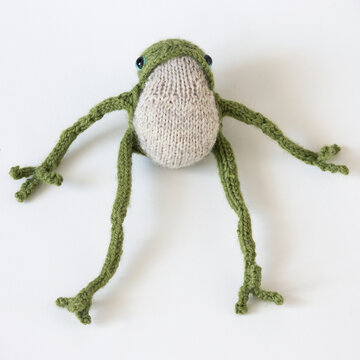 Knitted green frog with long legs