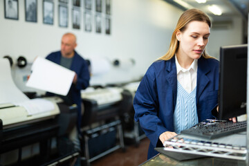 Caucasian woman using computer in printing office, pushing buttons on keyboard.