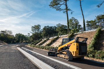 Mini-Carregadeira compacta ou Carregadeira de esteiras  numa obra de construção de estradas a...