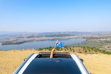 Woman holding Australia flag from the open car sunroof,  window driving along the serpentine road...