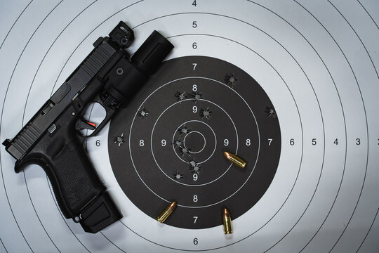 A shooting target with bullet holes in the center and a tactical pistol with a flashlight.