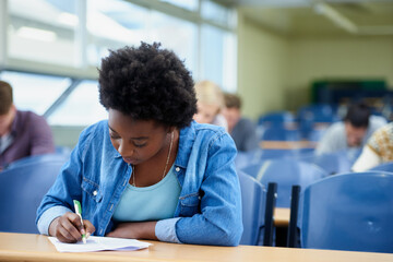 Writing, university and black woman student in classroom studying for test, exam or assignment. Education, college and female person working on project with knowledge in lecture hall for learning. - obrazy, fototapety, plakaty