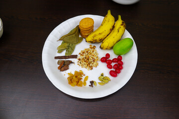 Tray of Ingredients Biscuits, Banana, Lemon, Bay Leaf, Cinnamon, Raisins, Almonds, Cardamom, Cloves, and Cherry Fruit 