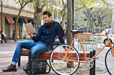Happy, city and smile with man, tablet and bicycle with adventure and digital app with email and social media. Person on bench, outdoor and New York with guy and technology with connection and typing