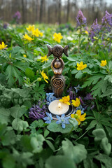 Goddess Candlestick with candle on floral meadow, abstract natural background. Symbol of the Triune...