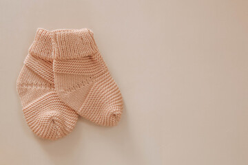 Knitted booties for a newborn on a beige background. Shoes for newborns