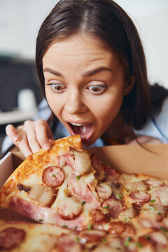 Hungry Woman Holding Pizza Box With Mouth Wide Open, Eagerly Reaching For A Slice Of Pizza In Front Of Her