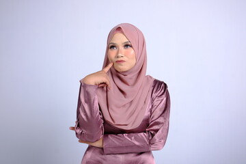 Beautiful Asian Muslim woman in hijab with questioning expression, with index finger on face. Isolated white background.